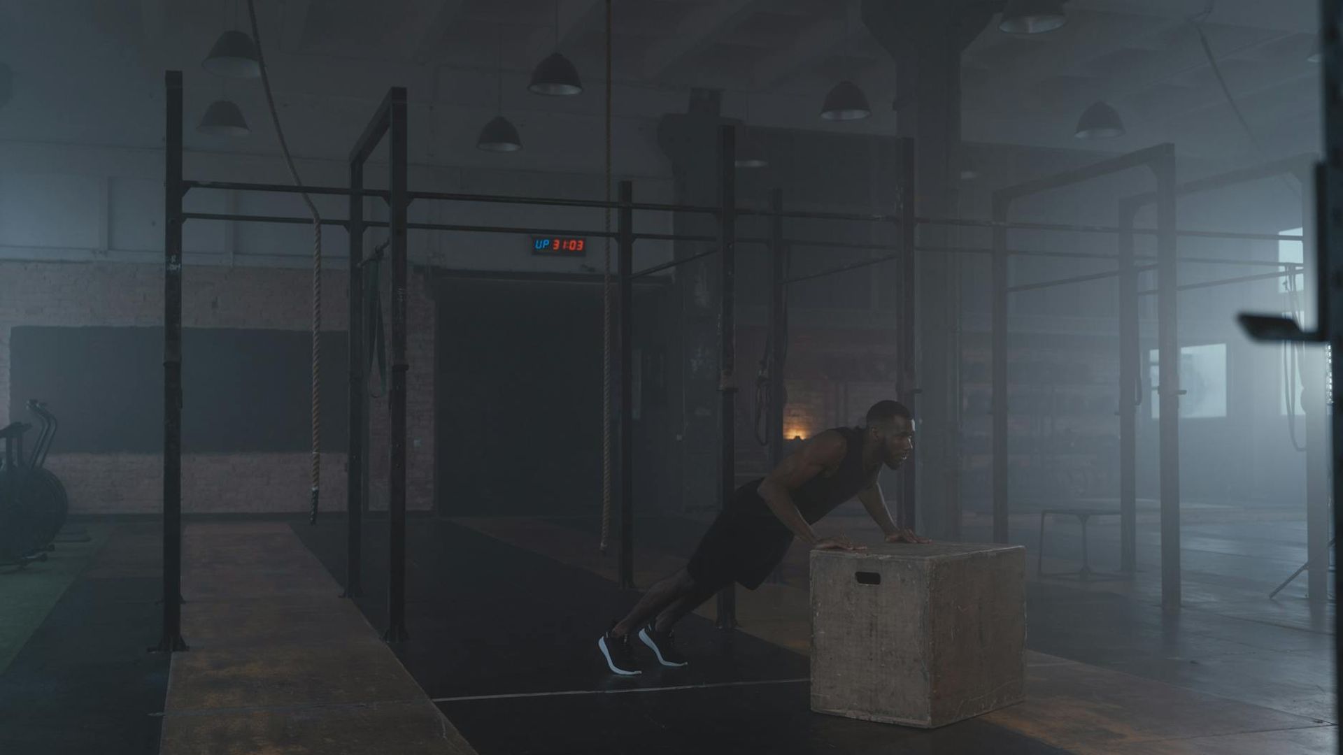 Athletic man performing strength exercises in a dark gym atmosphere